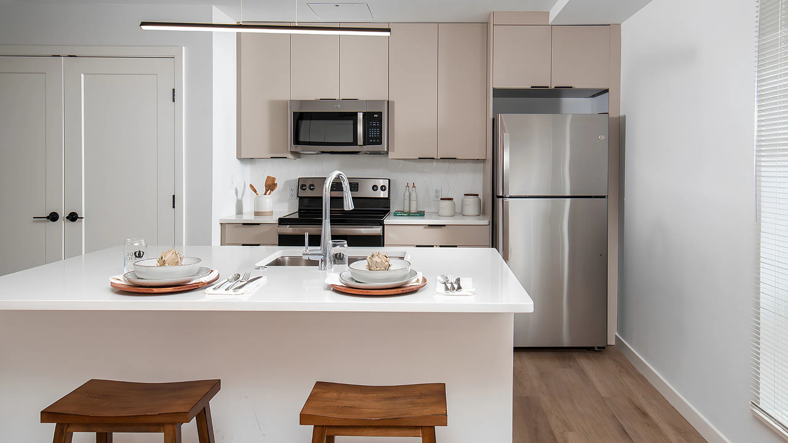 Modern kitchen with sleek stainless steel appliances, elegant cabinetry, and a chic white island with cozy wooden stools.