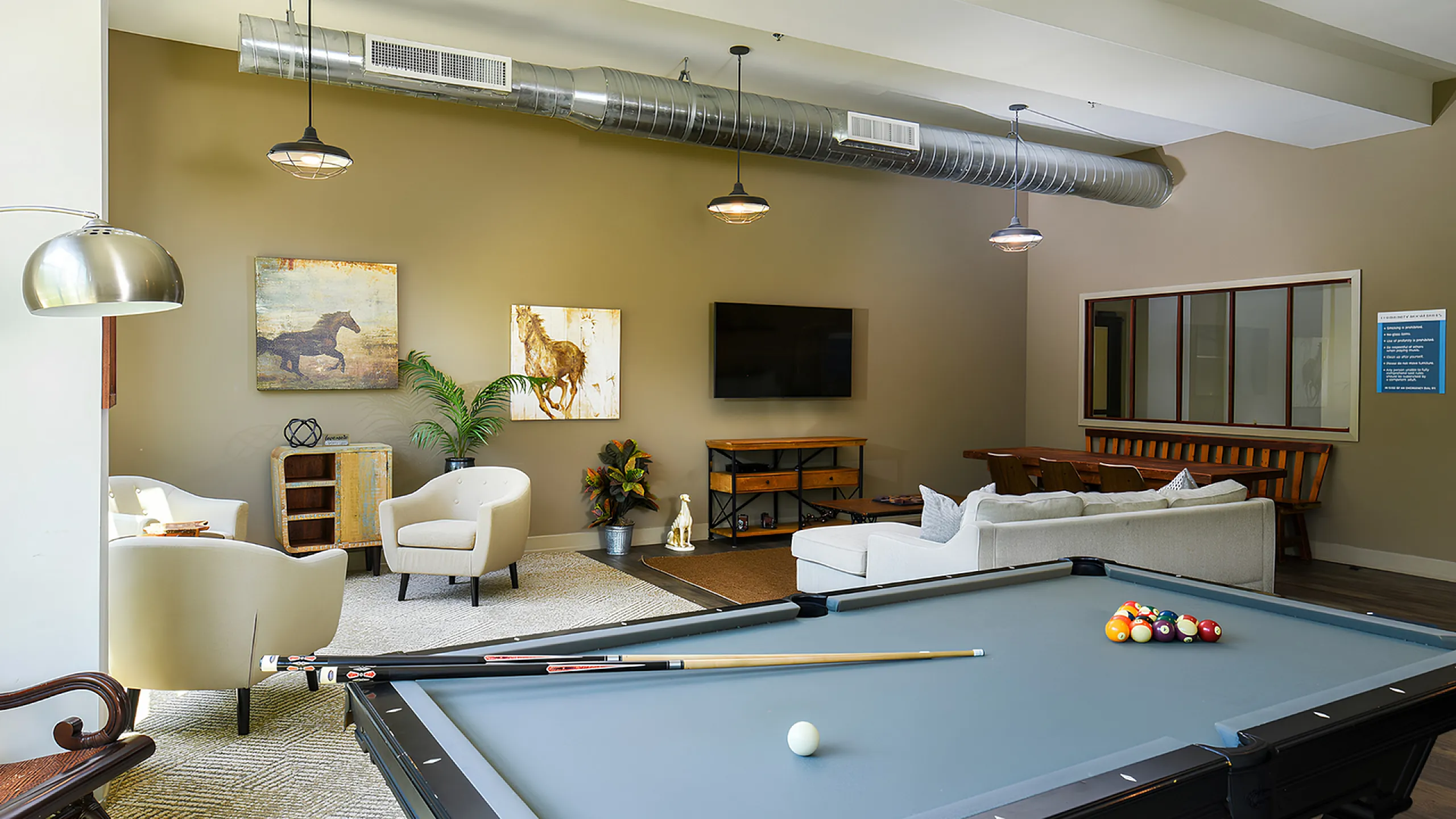 Chic apartment lounge featuring a stylish billiards table, cozy seating area, and modern decor with industrial touches.