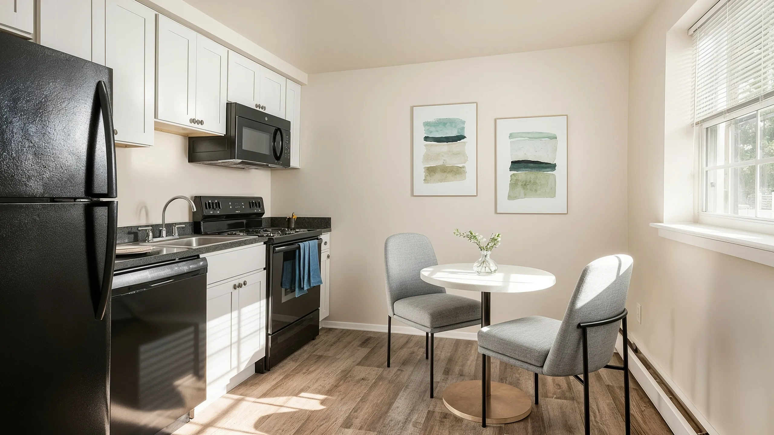Bright, modern kitchen with sleek black appliances, elegant white cabinetry, and a cozy dining nook with stylish decor.