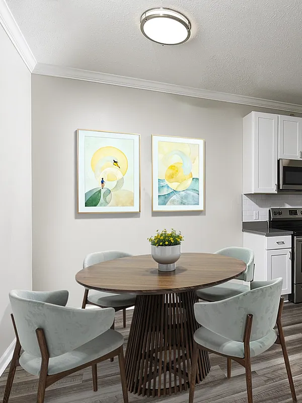 Elegant apartment kitchen with modern stainless steel appliances, sleek cabinetry, and a cozy dining area with stylish artwork.