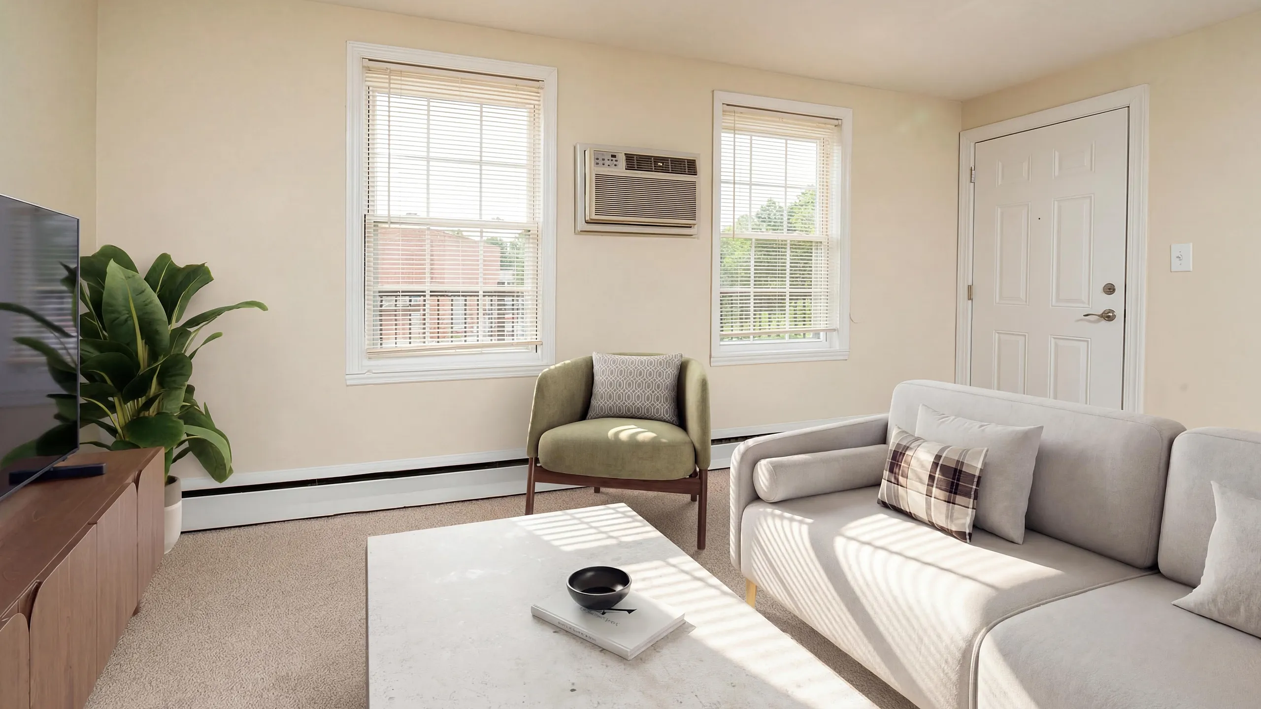 Bright and cozy living room with modern furnishings, large windows, and a sleek air conditioning unit. Ideal space for relaxation and entertainment.