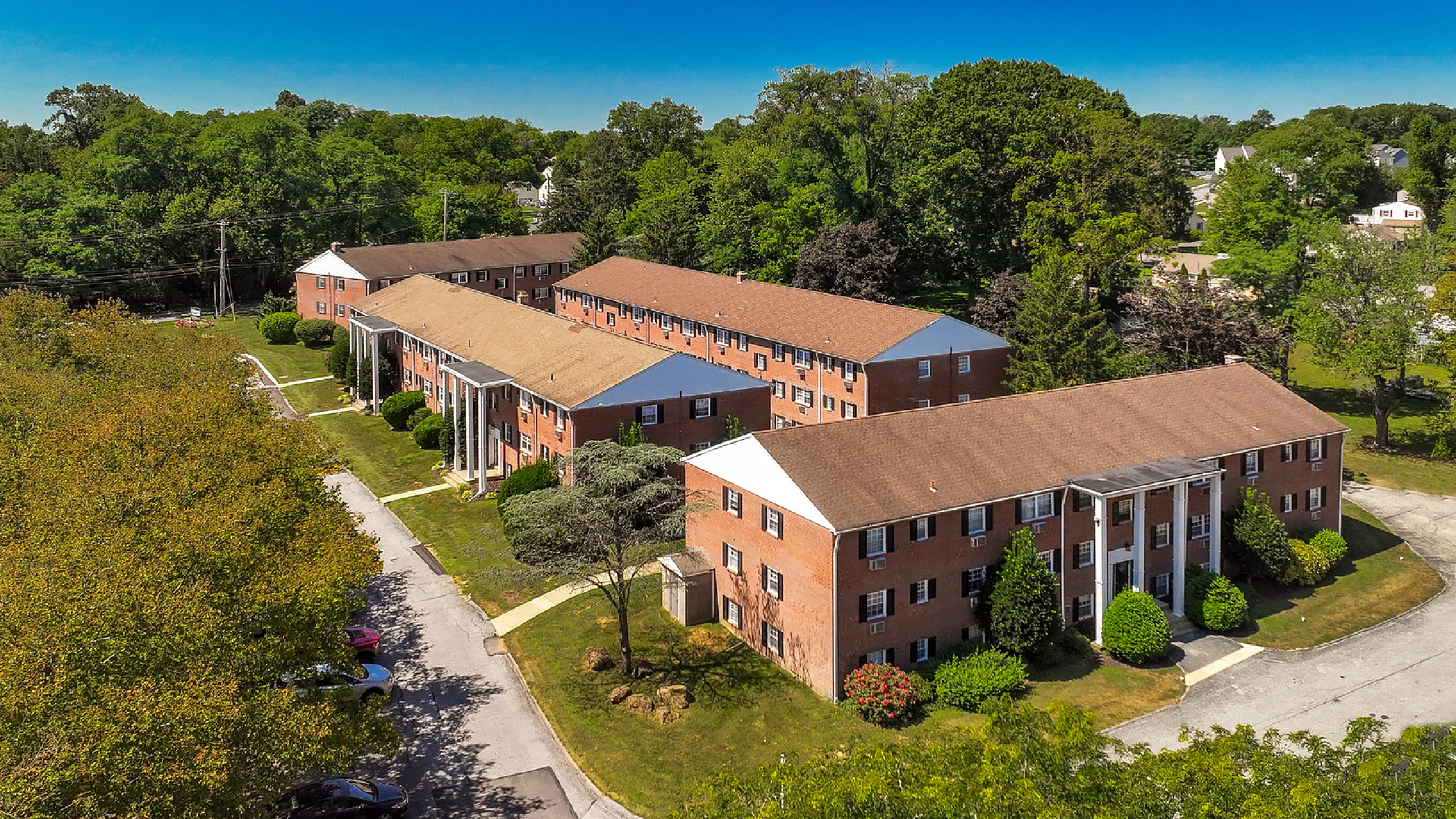 Charming apartment complex nestled in lush greenery with inviting traditional architecture and ample parking.