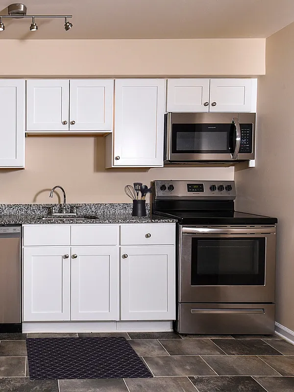 Modern kitchen with sleek stainless steel appliances, granite countertops, and elegant white cabinetry.