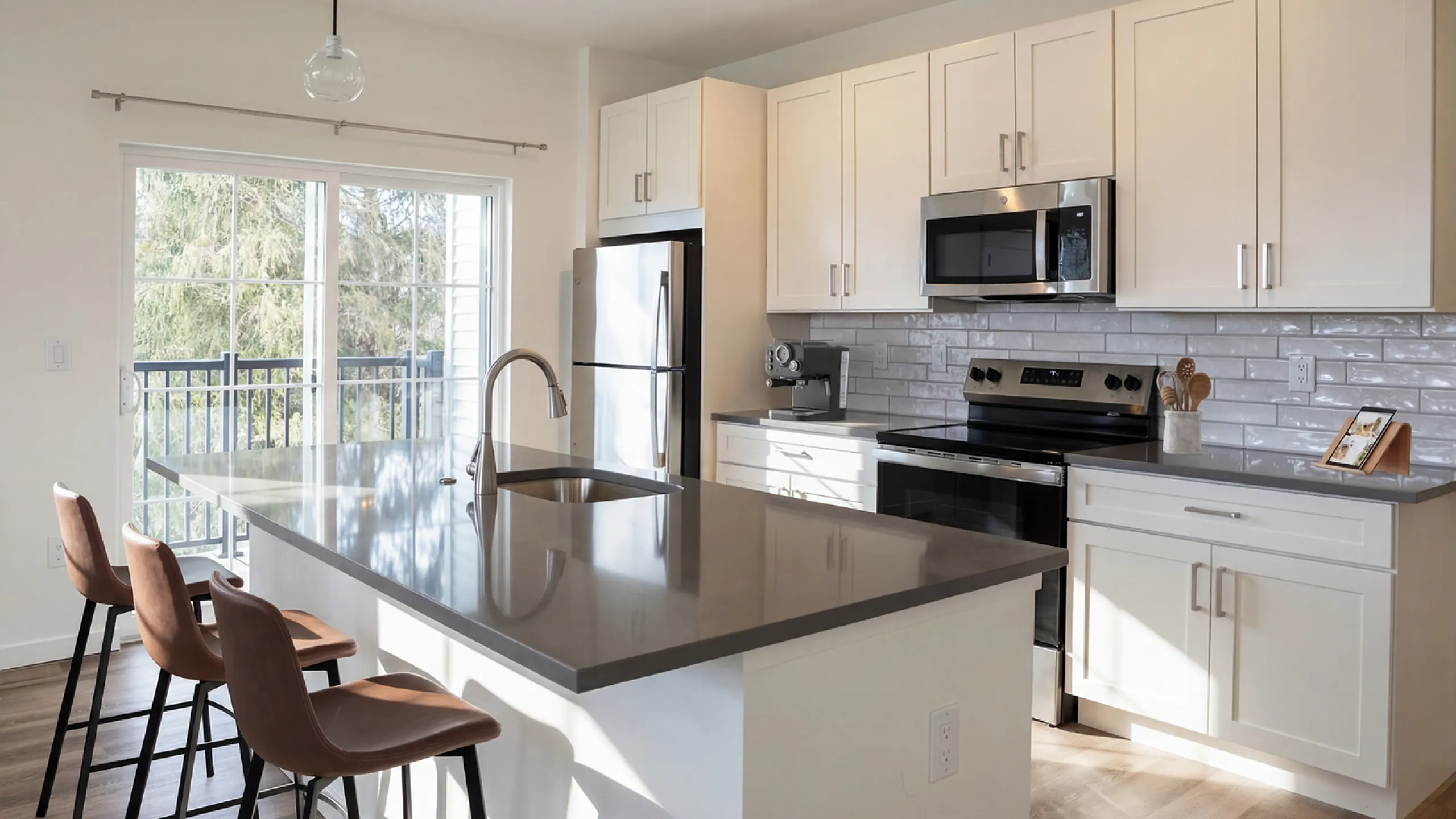 Modern kitchen with sleek countertops, stainless steel appliances, and stylish bar seating overlooking a sunny balcony view.