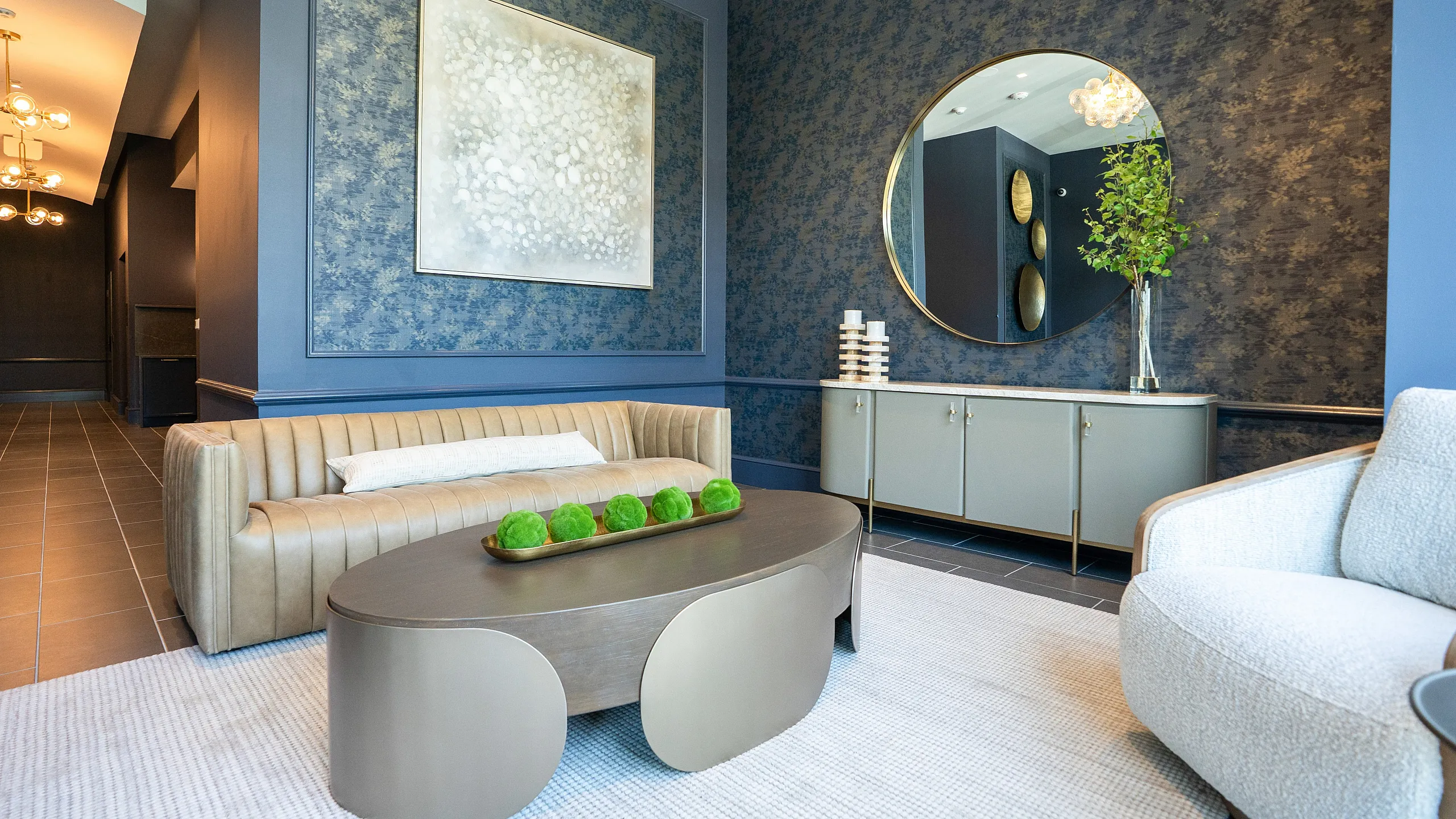 Chic living room with modern decor, featuring a sleek tan leather sofa, elegant coffee table, and artistic wall accents.
