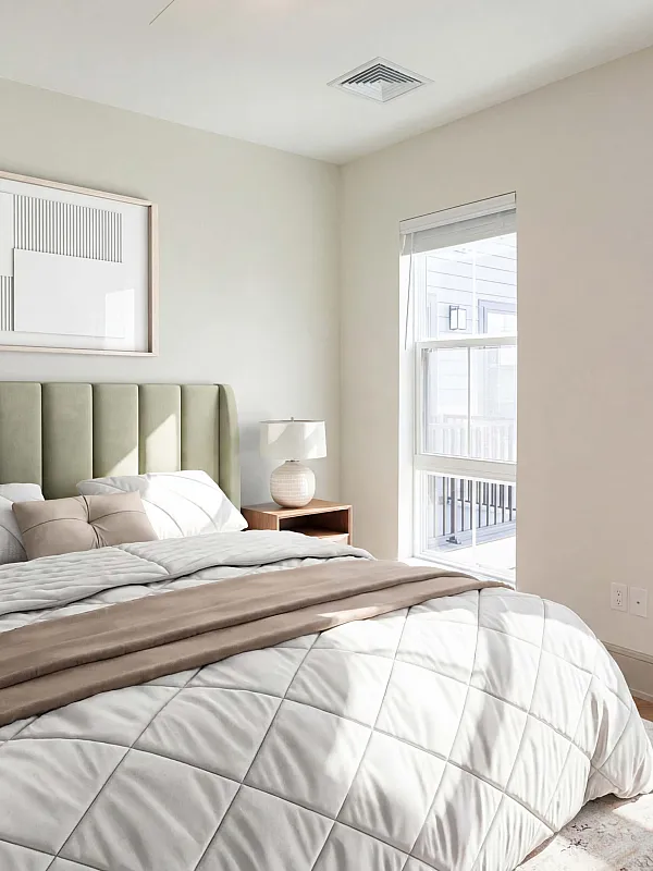 Bright and elegant bedroom featuring a plush bed, modern artwork, and sunlit windows with a touch of greenery.
