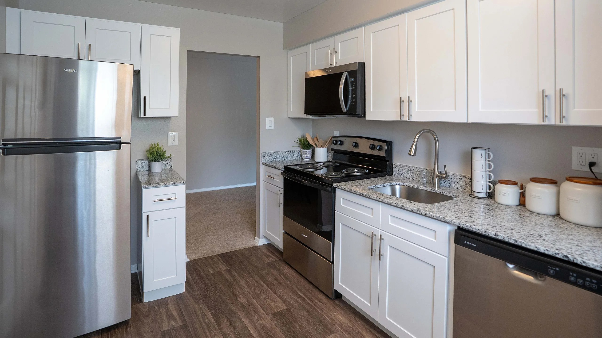Modern kitchen featuring stainless steel appliances, sleek granite countertops, and elegant white cabinetry.