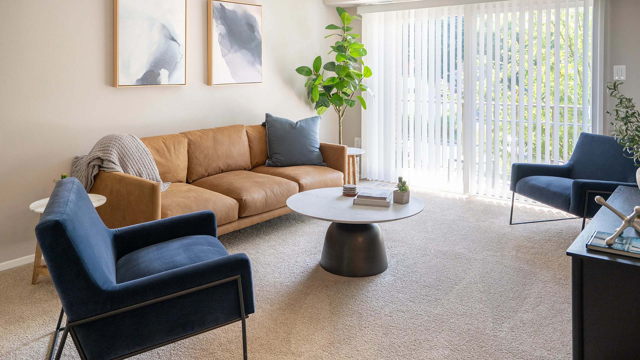Bright, modern living room with a cozy tan sofa, chic blue chairs, and large windows offering natural light.