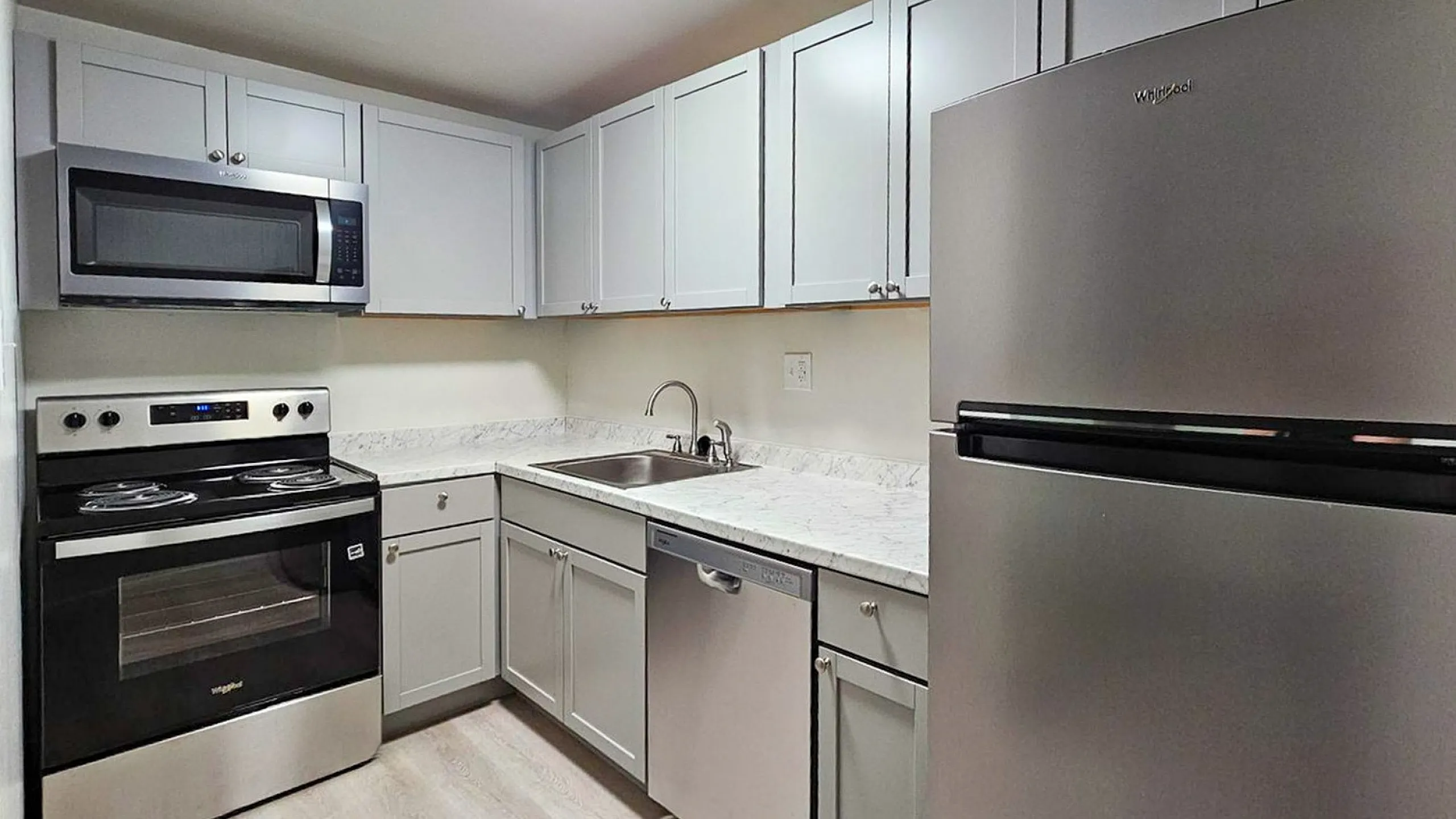 Modern kitchen with sleek stainless steel appliances, elegant white cabinetry, and stylish marble countertops.