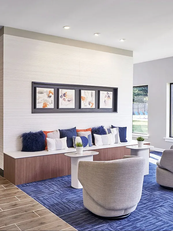 Contemporary lounge area with cozy seating, vibrant blue accents, and large windows offering scenic outdoor views.