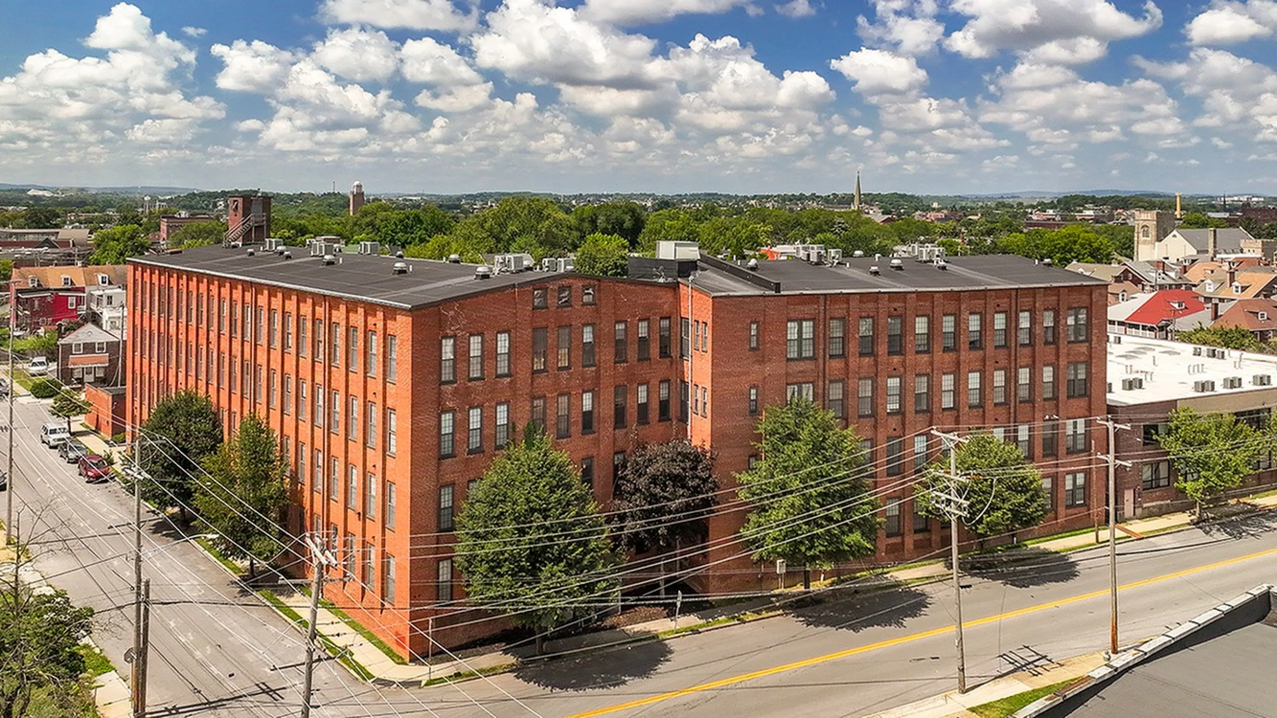 Impressive red brick building nestled in a vibrant urban neighborhood, surrounded by lush greenery and scenic views.