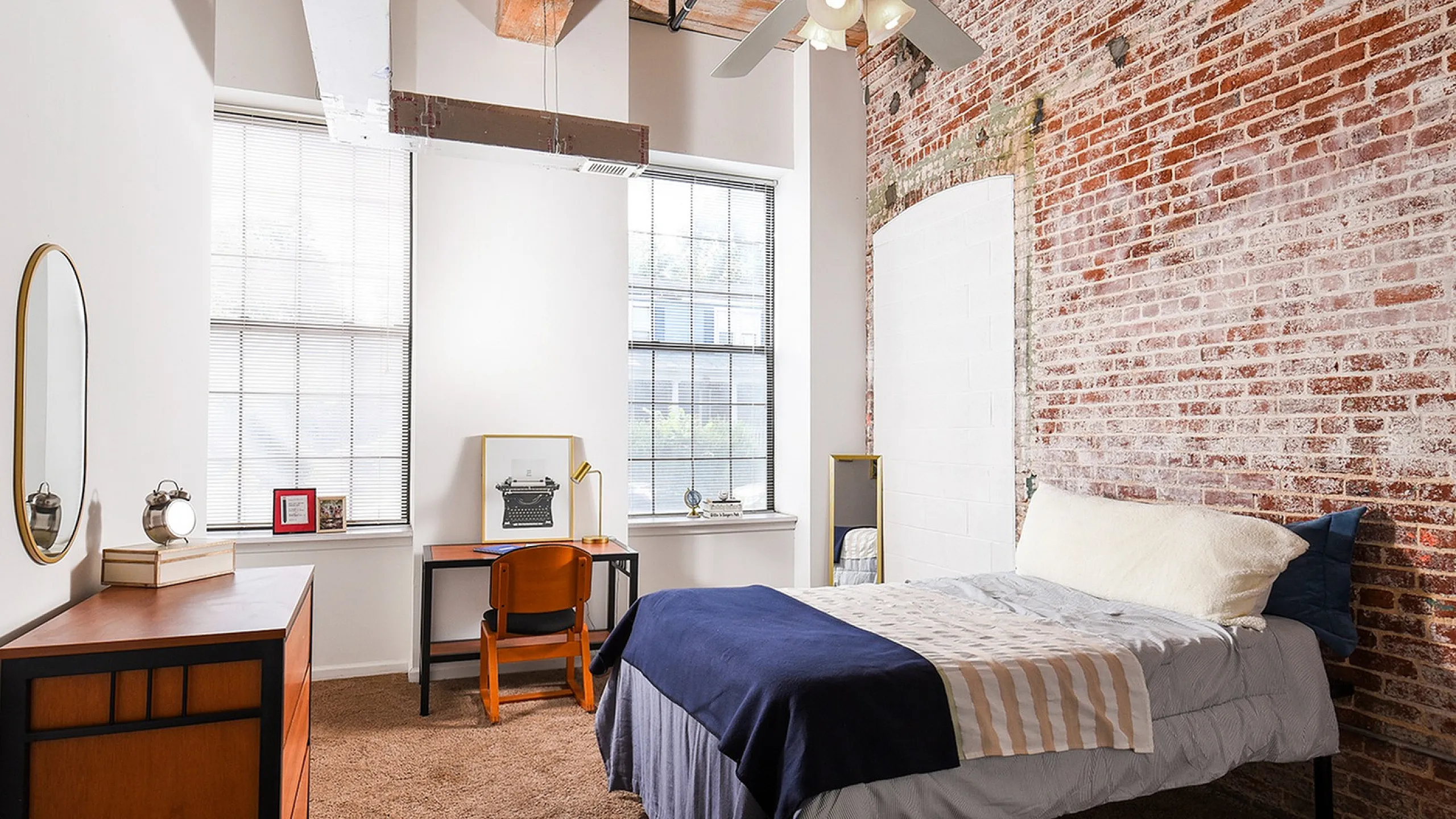 Chic industrial-style bedroom featuring exposed brick walls, a cozy bed, and a stylish workspace with natural light.