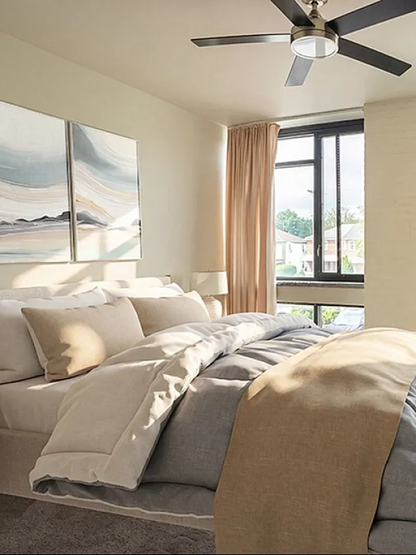 Bright and airy bedroom with large windows, modern decor, and a comfortably inviting bed, showcasing natural light and serene ambiance.