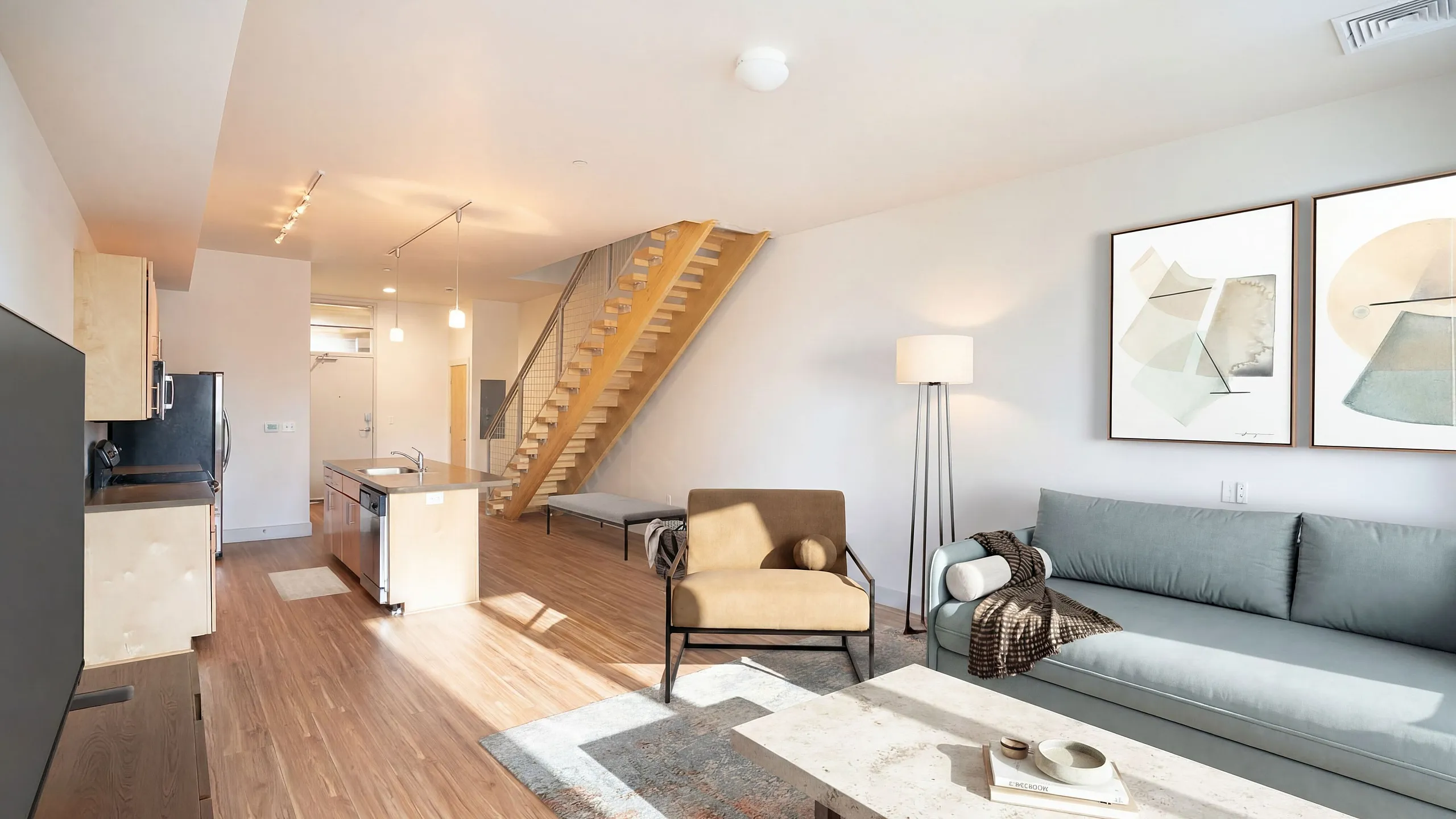 Modern open-concept apartment with stylish kitchen, cozy living room, and inviting wooden staircase.