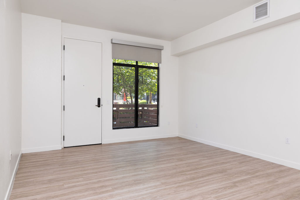 Bright and spacious interior featuring sleek wood flooring, large window, and modern accents.