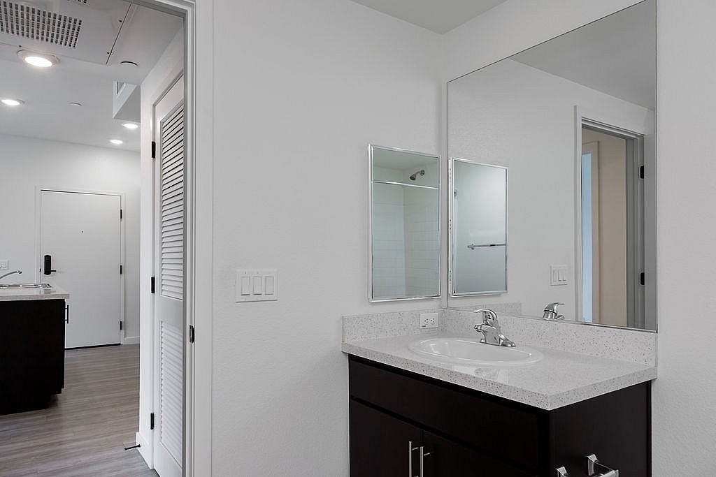 Contemporary bathroom with sleek fixtures and ample natural light, adjacent to a modern, well-lit entrance hallway.