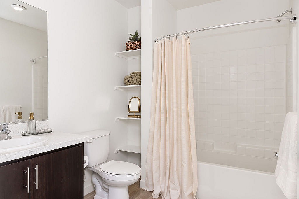 Elegant bathroom featuring a sleek vanity, modern fixtures, and a soothing white decor with ample storage space.
