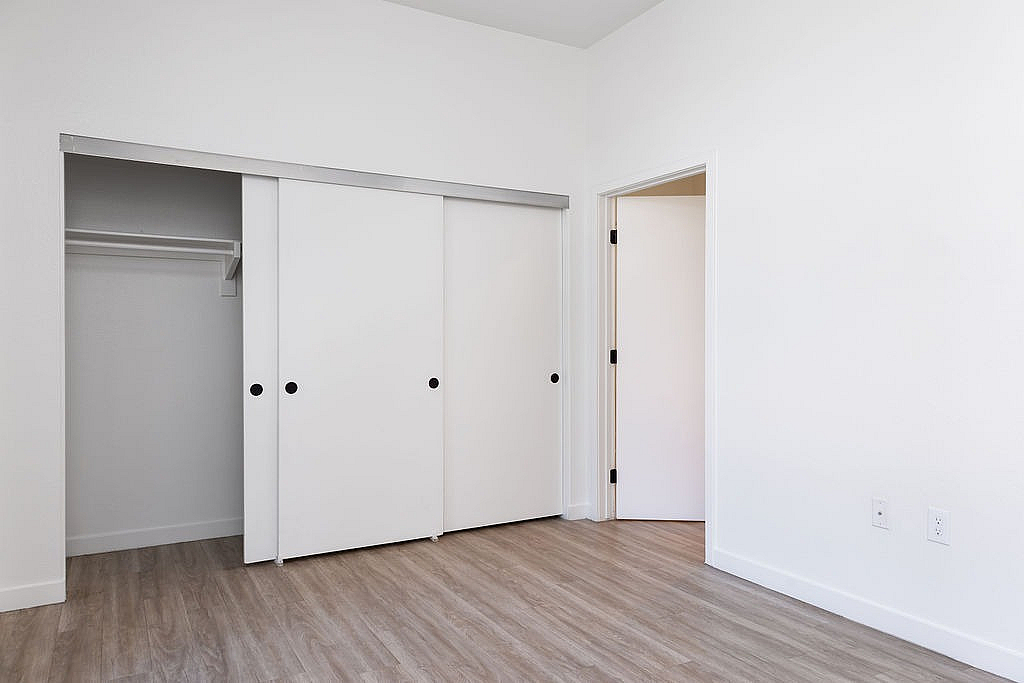 Bright and modern bedroom with sleek sliding closet doors and elegant wood flooring.