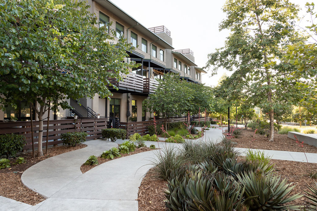 Modern apartment building with lush landscaping and inviting pathways offering a serene living environment.