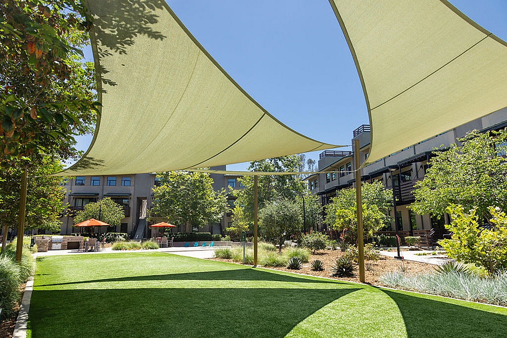 Community courtyard with pet park, elegant shade sails, lush greenery, and comfortable seating areas.