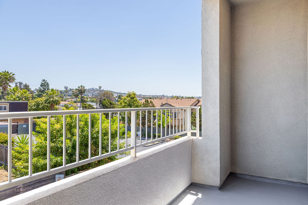 Serene townhome balcony with stunning views of lush greenery and distant hills under a clear blue sky.