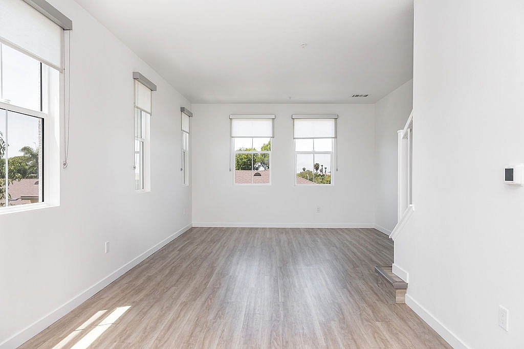 Bright and airy room with wood flooring, large windows, and stylish roller blinds, perfect for a modern living space.