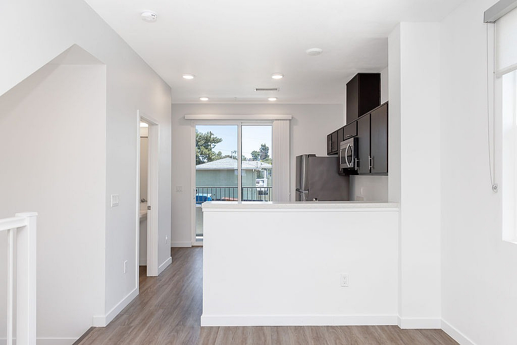 Modern open kitchen and half bath with sleek cabinetry and natural light streaming through large windows.