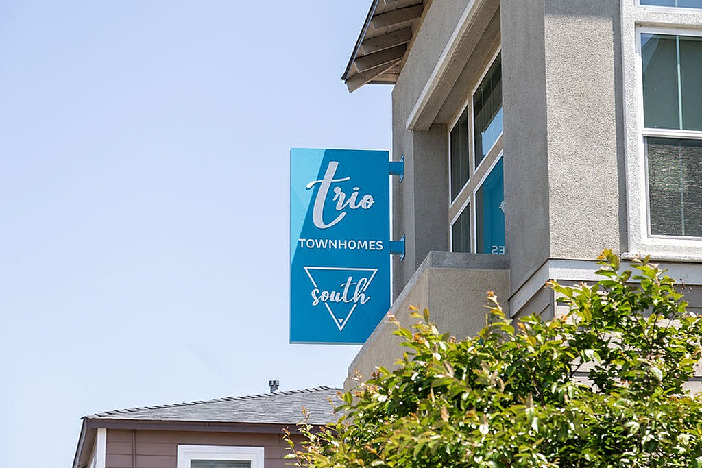 Modern Trio Townhomes South signage on a sunny day, perfect blend of urban and cozy living.