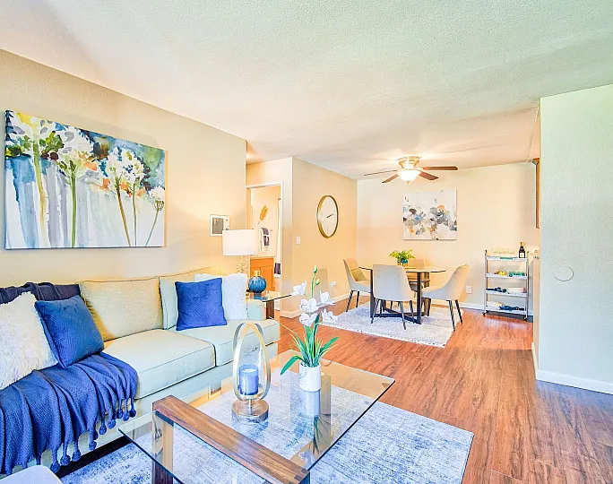 Charming and bright living space featuring a cozy sofa with vibrant cushions, elegant decor, and a welcoming dining area with modern chairs and stylish artwork.