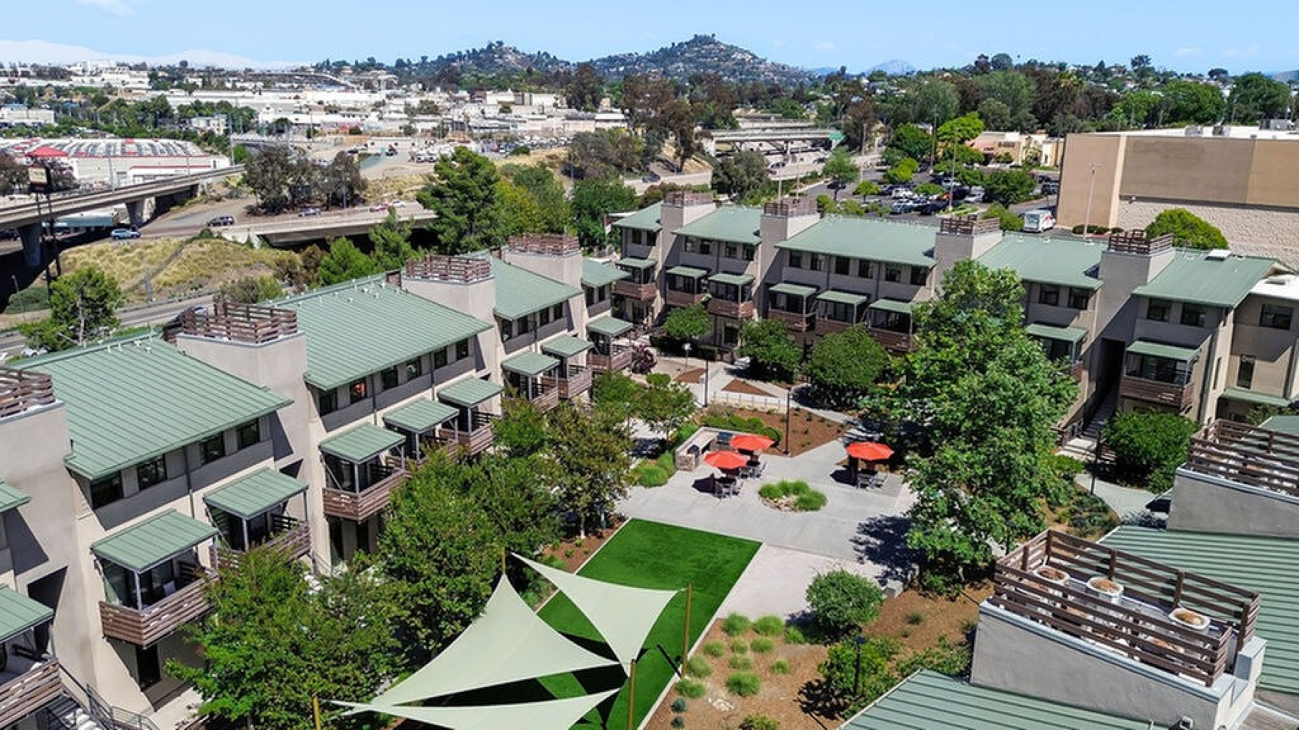 Charming apartment community with lush greenery, modern architecture, and inviting outdoor seating area, ideal for relaxation and community living.