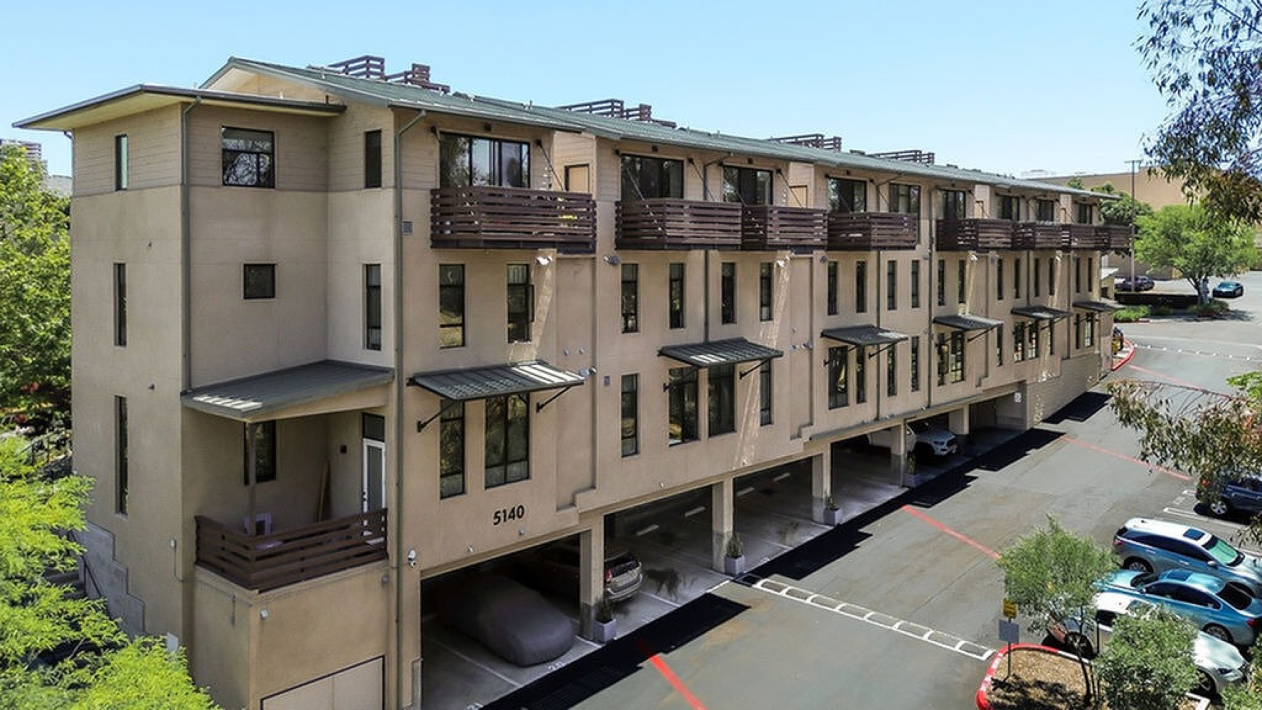 Impressive multi-story apartment building with modern architecture, featuring spacious balconies and covered parking in a serene neighborhood.