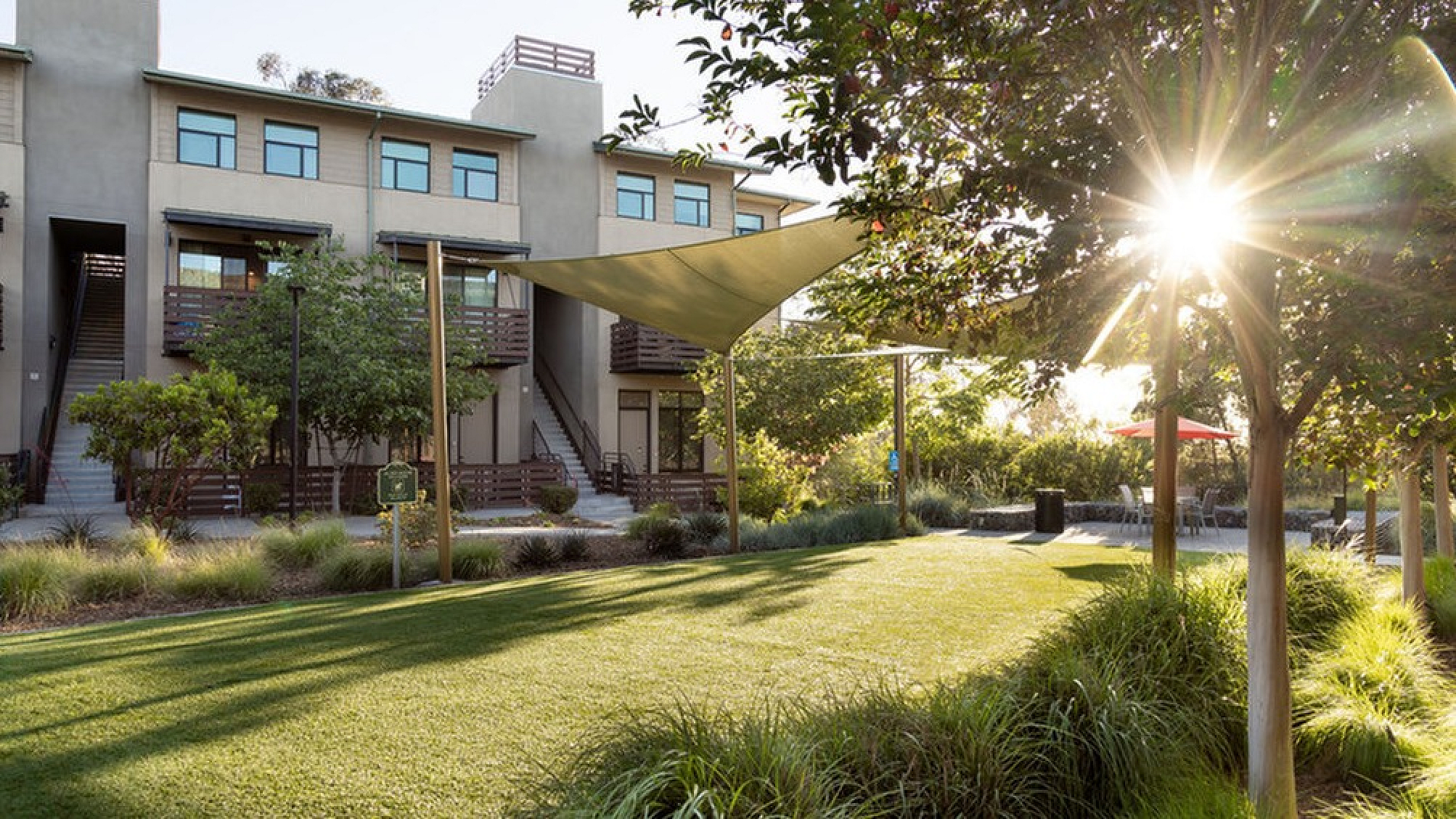 Charming apartment building with a beautifully landscaped garden, featuring lush greenery and a sunlit courtyard perfect for relaxation.