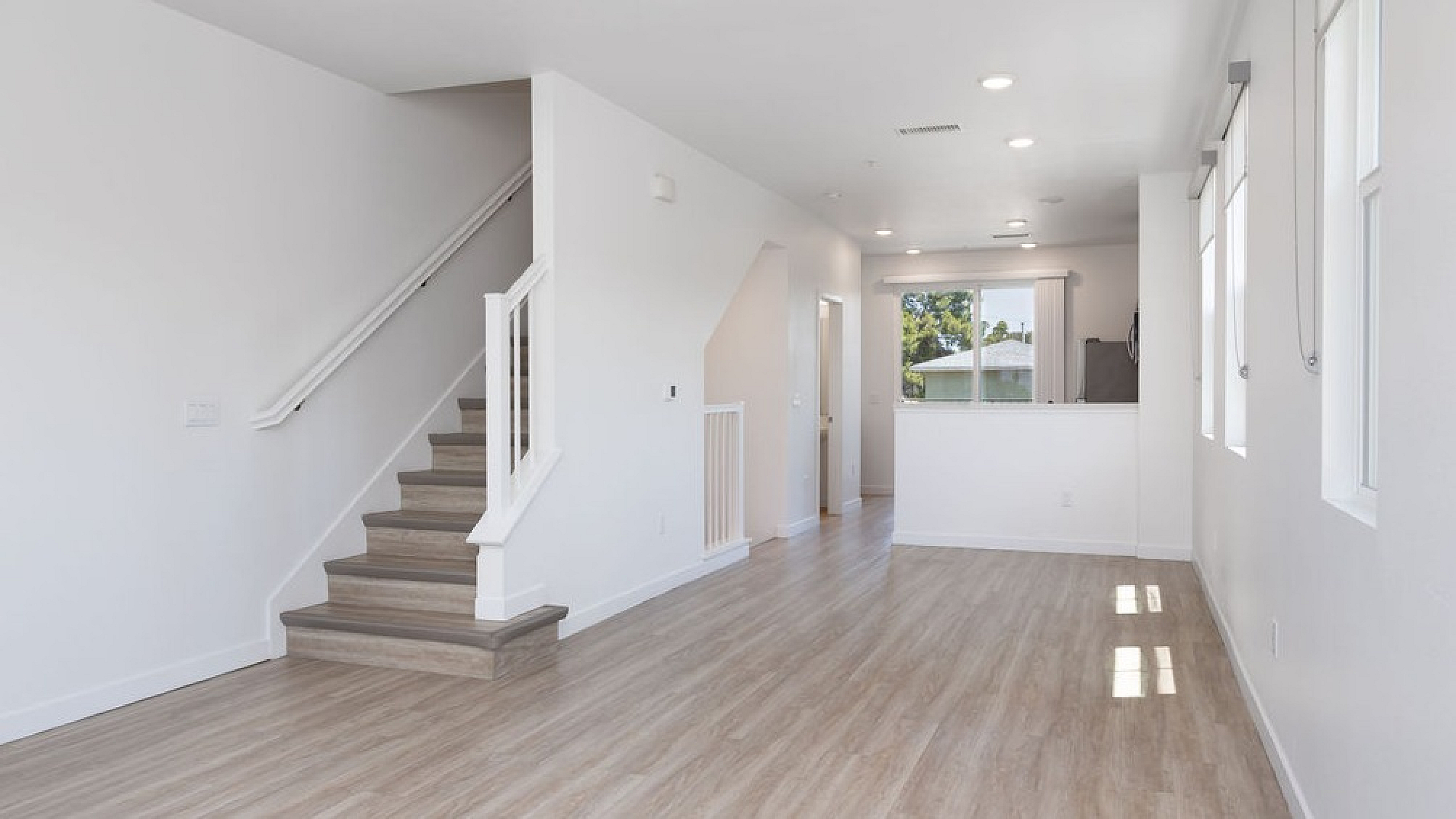 Bright and inviting open-concept living space featuring sleek hardwood floors, contemporary design, and abundant natural light.