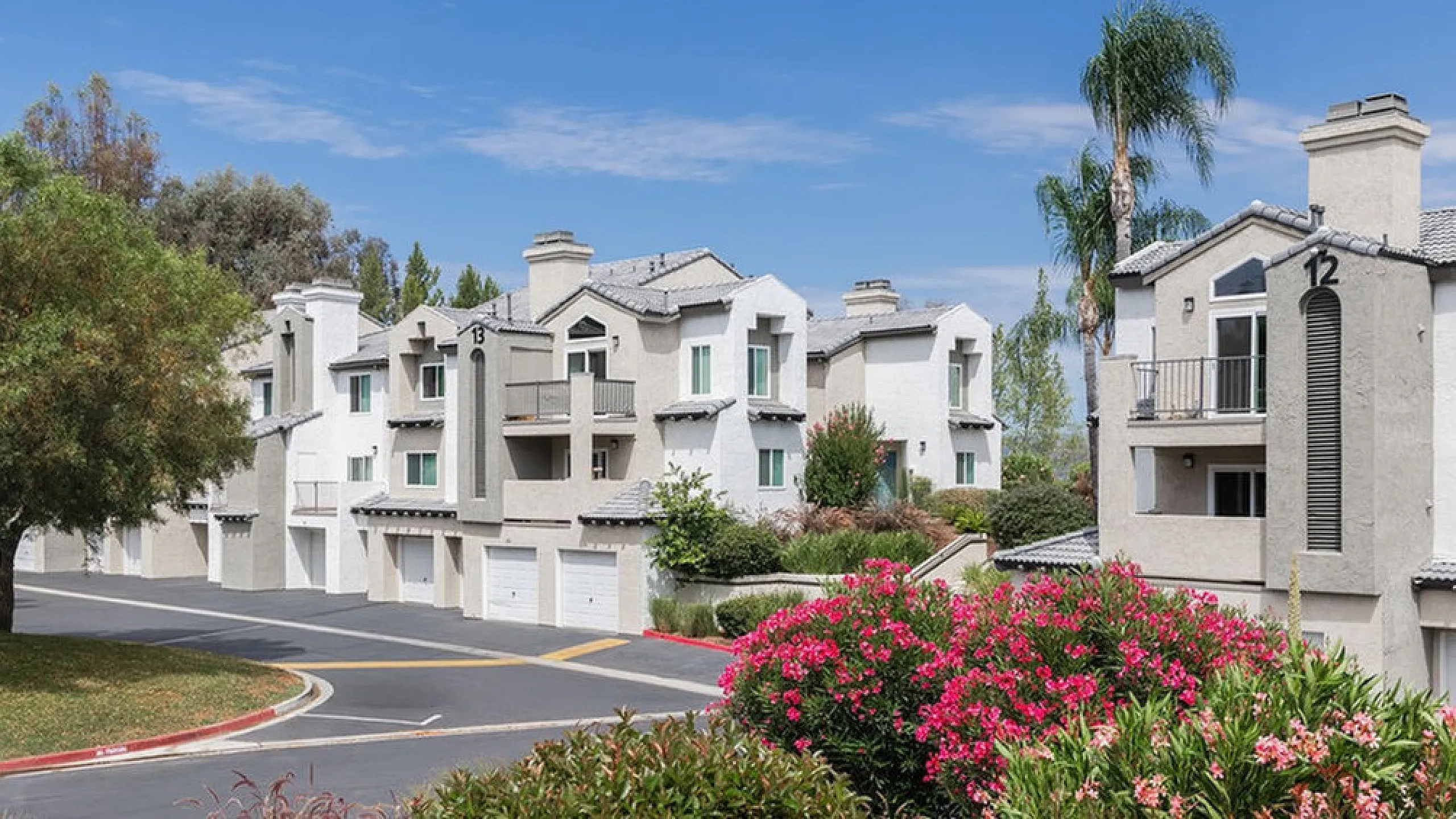 Charming apartment complex surrounded by lush landscaping and vibrant flowers, featuring modern architecture and a tranquil atmosphere.