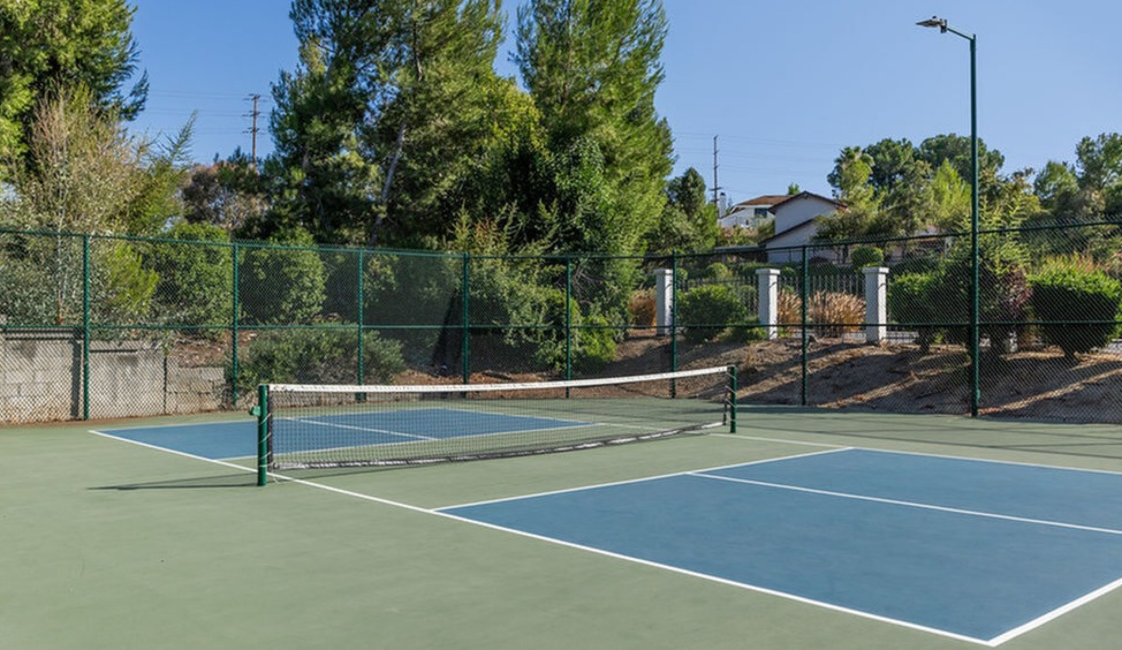 Inviting outdoor tennis court nestled in a serene green setting, perfect for sports enthusiasts and relaxation.