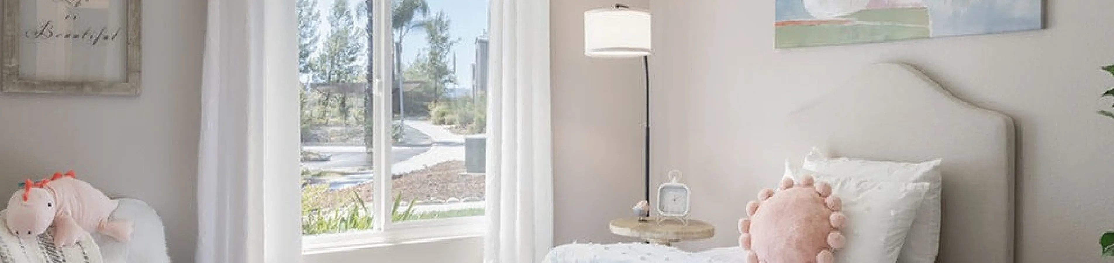 Bright and charming bedroom with cozy bed, modern decor, and a serene view through a large window.