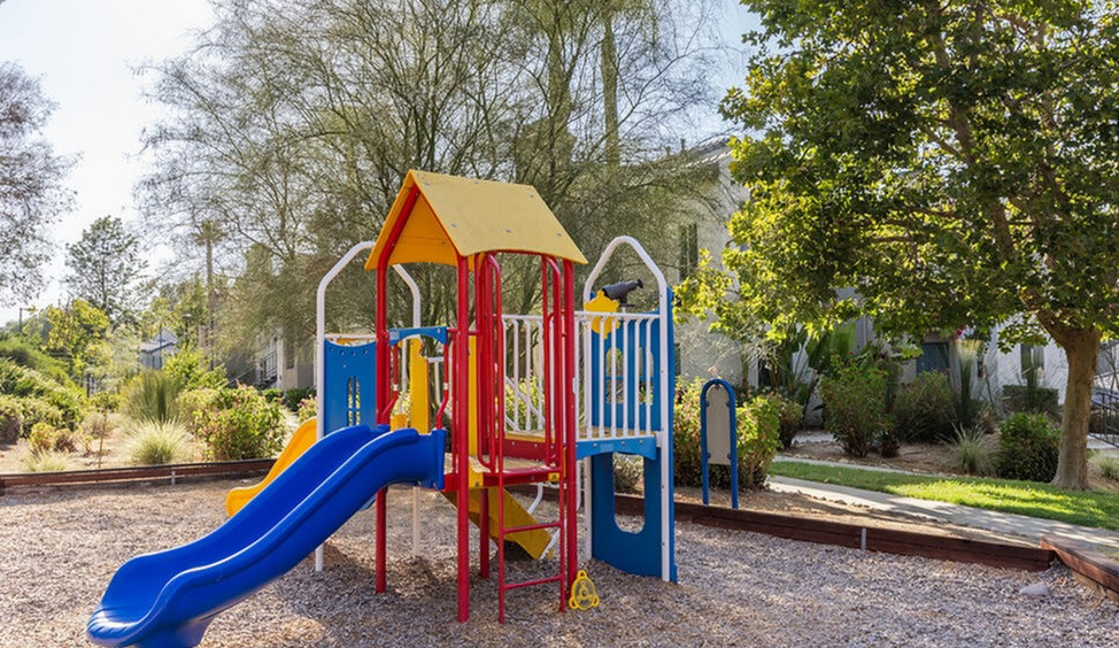 Charming playground nestled in a lush, scenic area featuring a colorful slide and climbing structures, perfect for family fun.