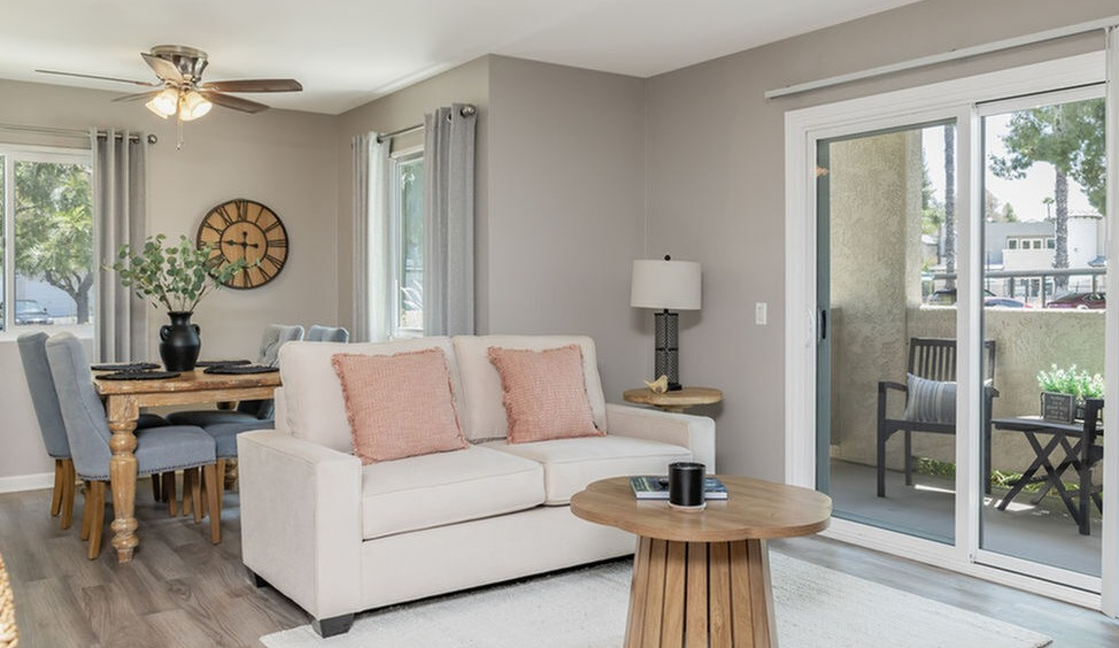 Bright and inviting living area with cozy sofa, rustic dining table, and sliding glass doors leading to a charming balcony.