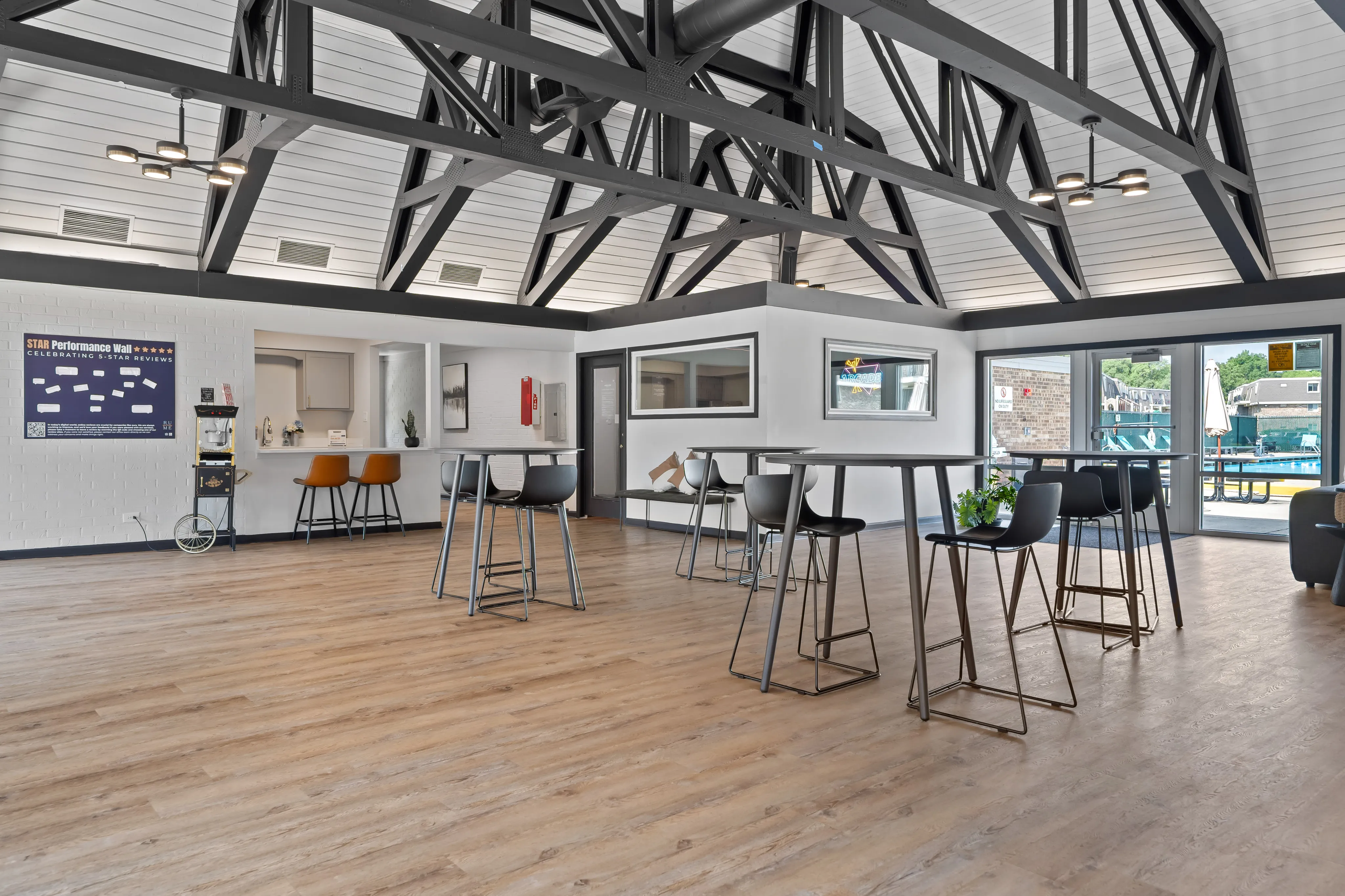 Chic open-concept clubhouse featuring high ceilings, modern bar seating, and poolside views with natural light.