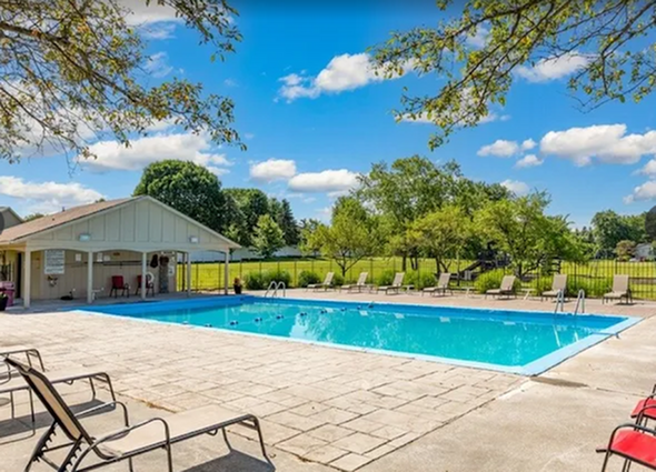 Inviting outdoor pool area with comfortable lounge chairs and a scenic view of lush greenery, perfect for relaxation and leisure.