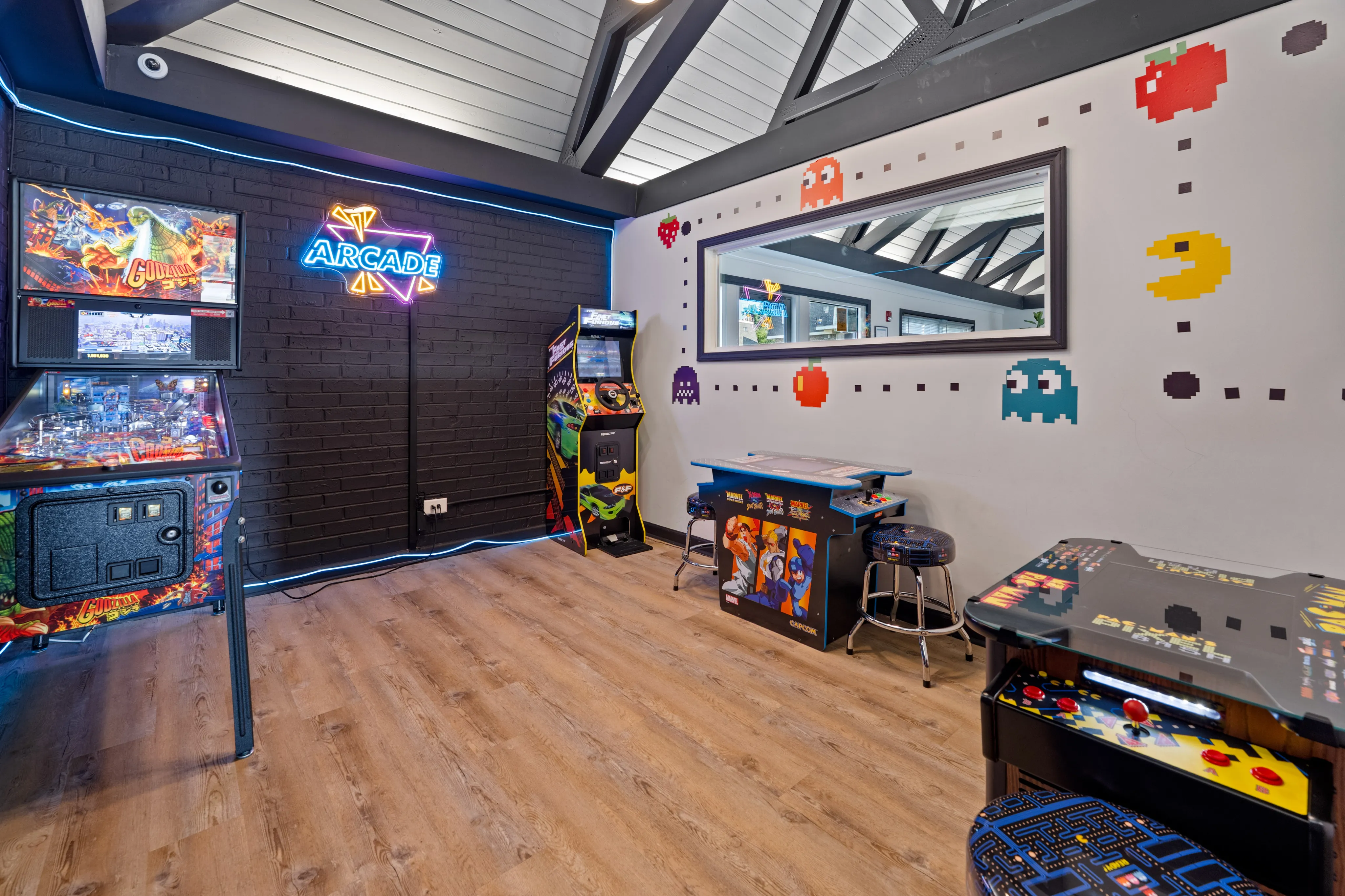 Vibrant game room with retro arcade machines, bright neon sign, and lively Pac-Man themed wall art.
