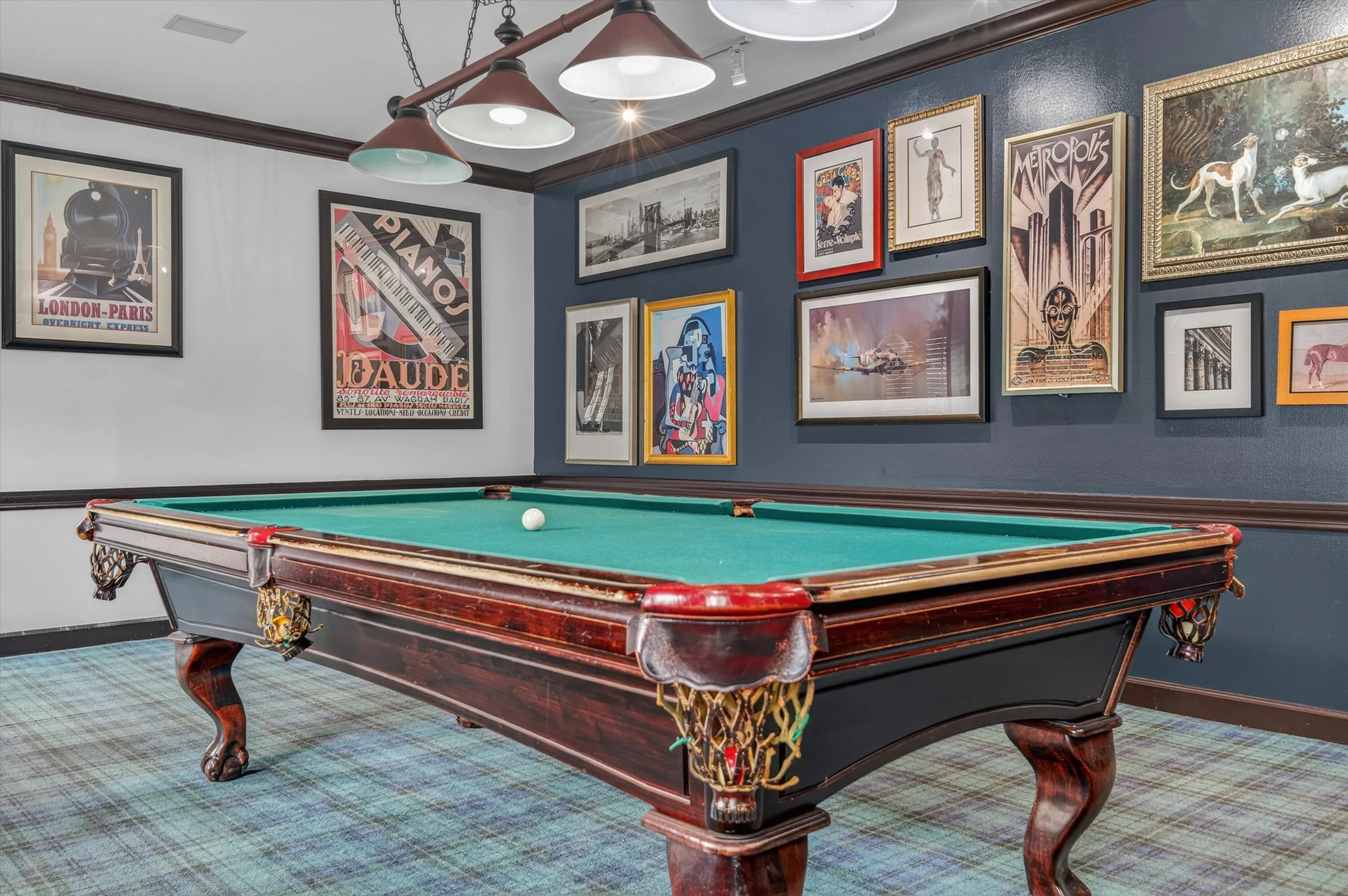 Chic game room with an elegant pool table, vintage-themed wall art, and ambient lighting creating a stylish recreational space.