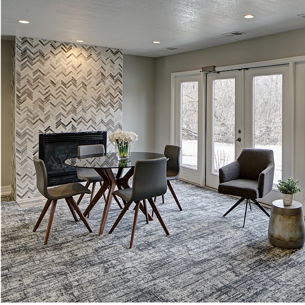 Chic living area featuring modern chairs, stylish chevron accent wall, and abundant natural light from large windows.