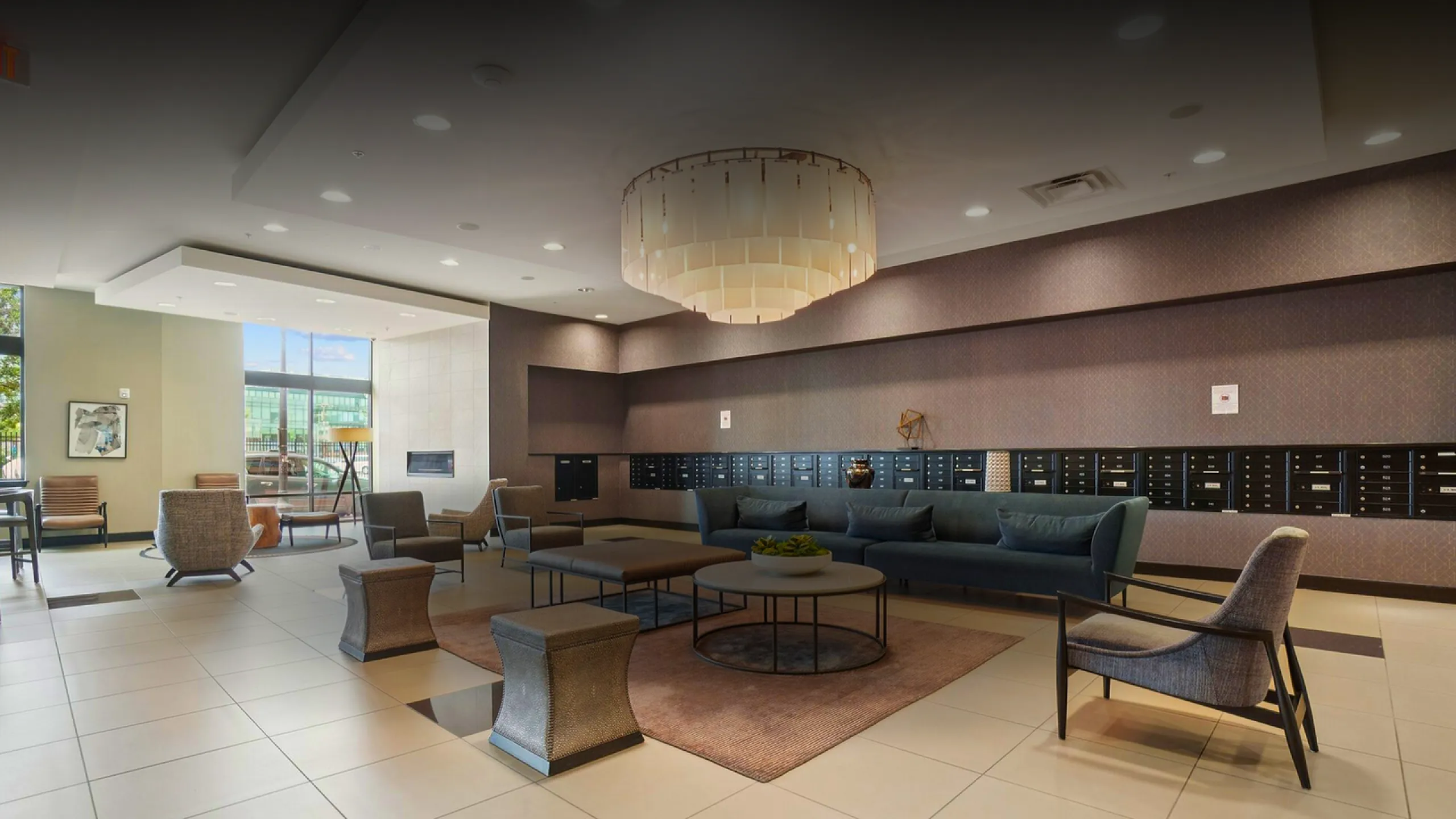 Elegant apartment lobby featuring contemporary decor, plush seating, and a grand chandelier.