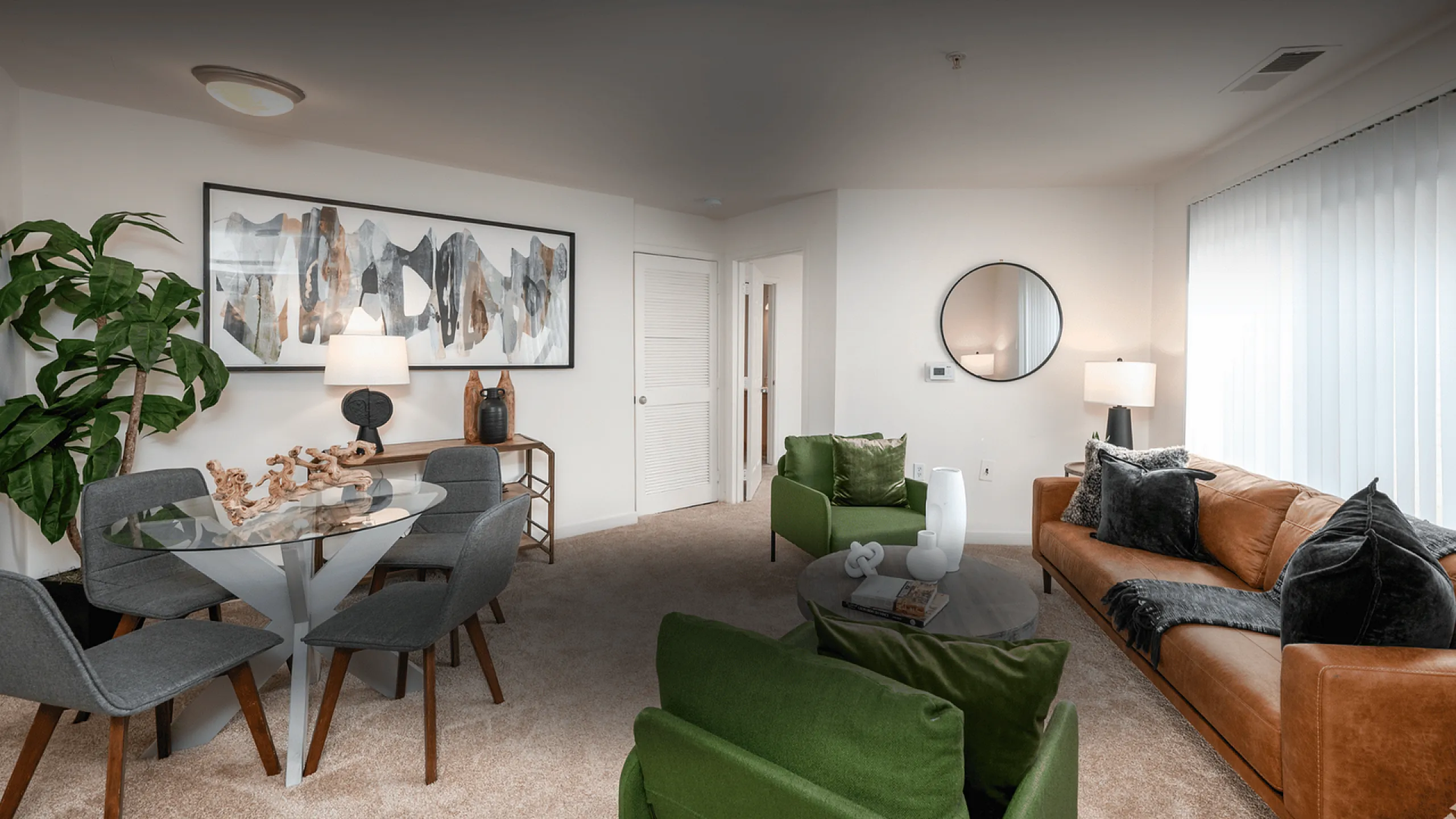 Modern living room featuring a chic brown leather sofa, stylish green armchairs, and a sophisticated glass dining table with contemporary decor.