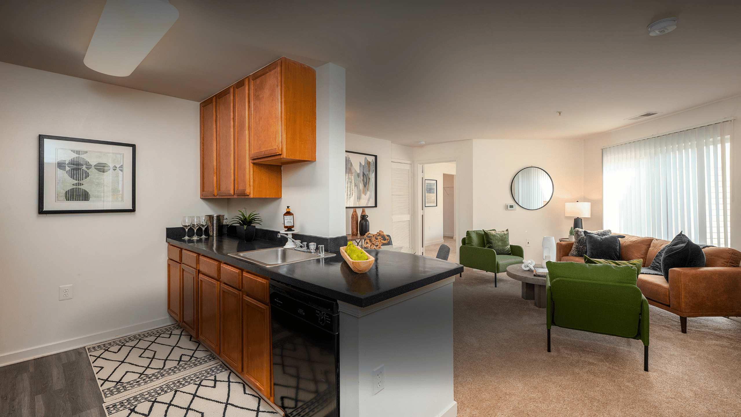Elegant open-plan living area showcasing a sleek kitchen with wooden cabinets and a cozy living room featuring a stylish sofa set and chic decor.