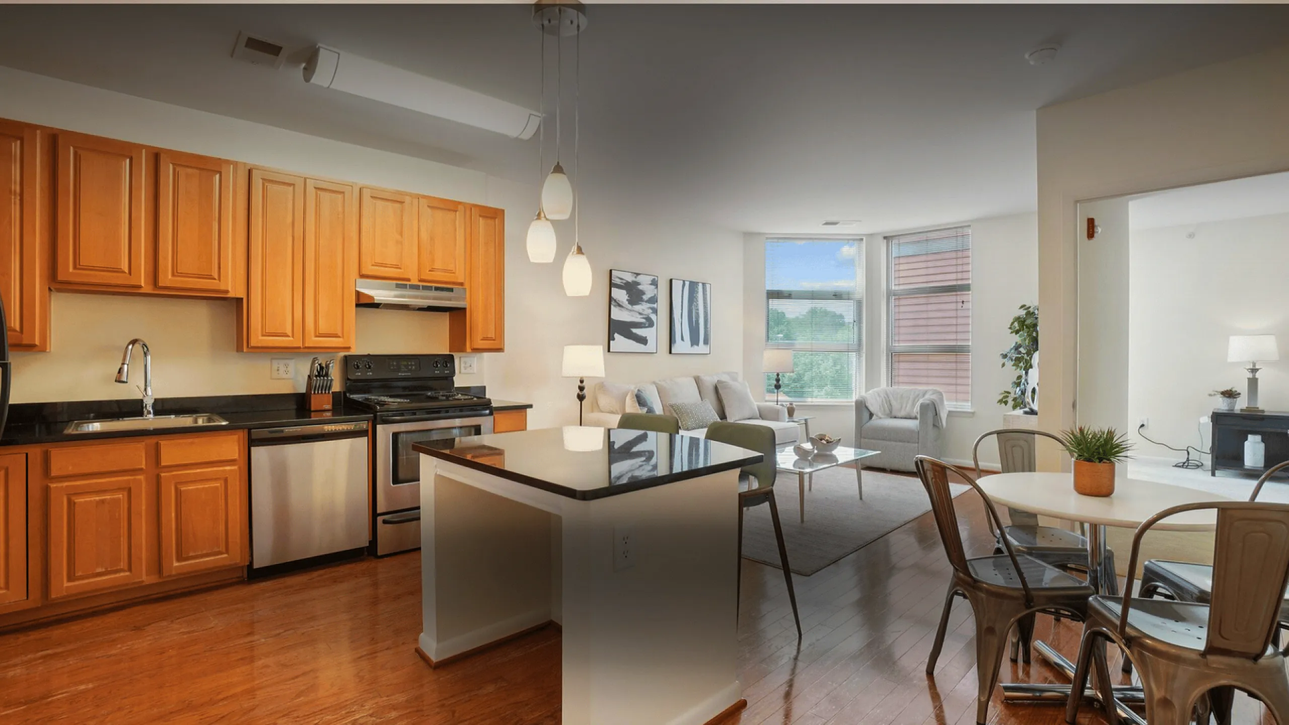 Elegant apartment interior featuring a modern kitchen with wooden cabinetry, open-concept living space with stylish lighting, and a cozy seating area with large windows.
