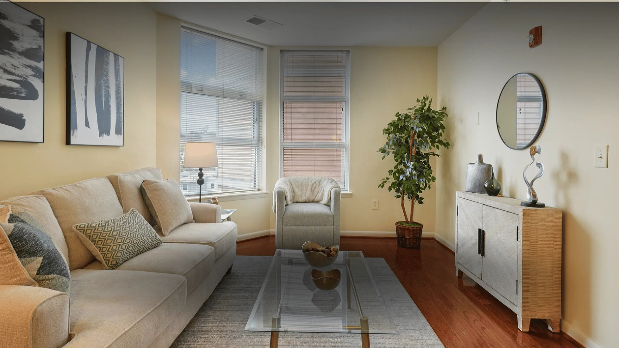 Charming living room with elegant beige sofa, sleek glass coffee table, large windows with natural light, and stylish decor harmonizing for a cozy atmosphere.
