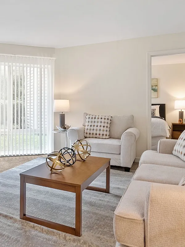 Bright and welcoming living room with elegant decor, featuring light beige sofas, a cozy coffee table, and large windows offering abundant natural light.