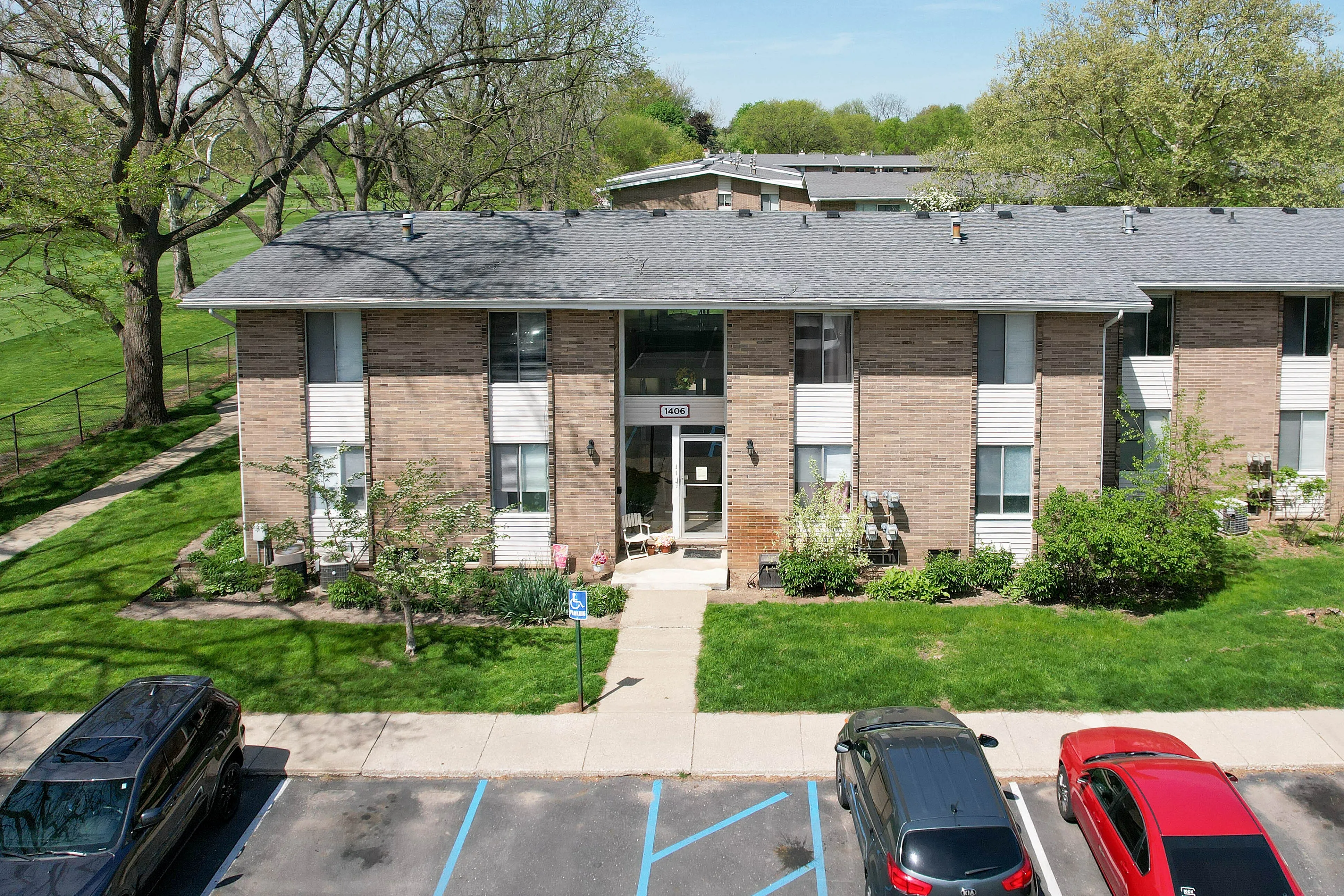 Charming apartment building set in a lush, green landscape with mature trees and well-maintained lawns, offering a peaceful residential environment.